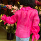 Rückenansicht einer afro-amerikanischen jungen Frau in einem Blumenladen, während sie eine blaue Jeans an hat und eine Seiden Organza Bluse in Hot Pink von Lola Tong.